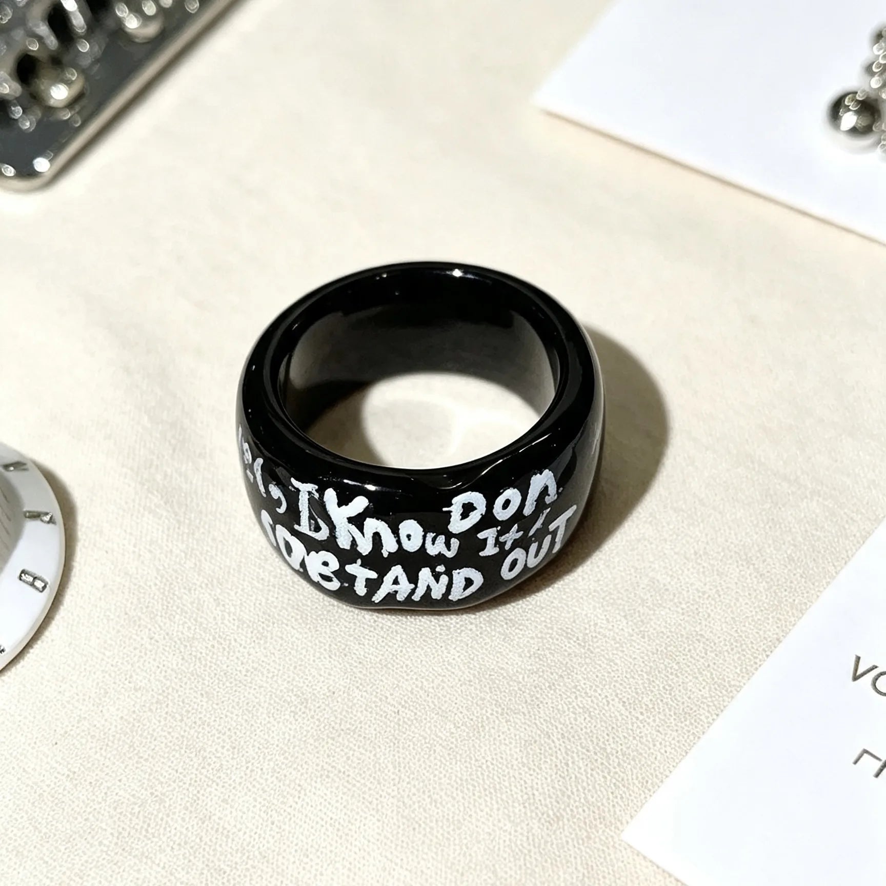 Close-up of glossy black ceramic ring with personalized engraved lettering.