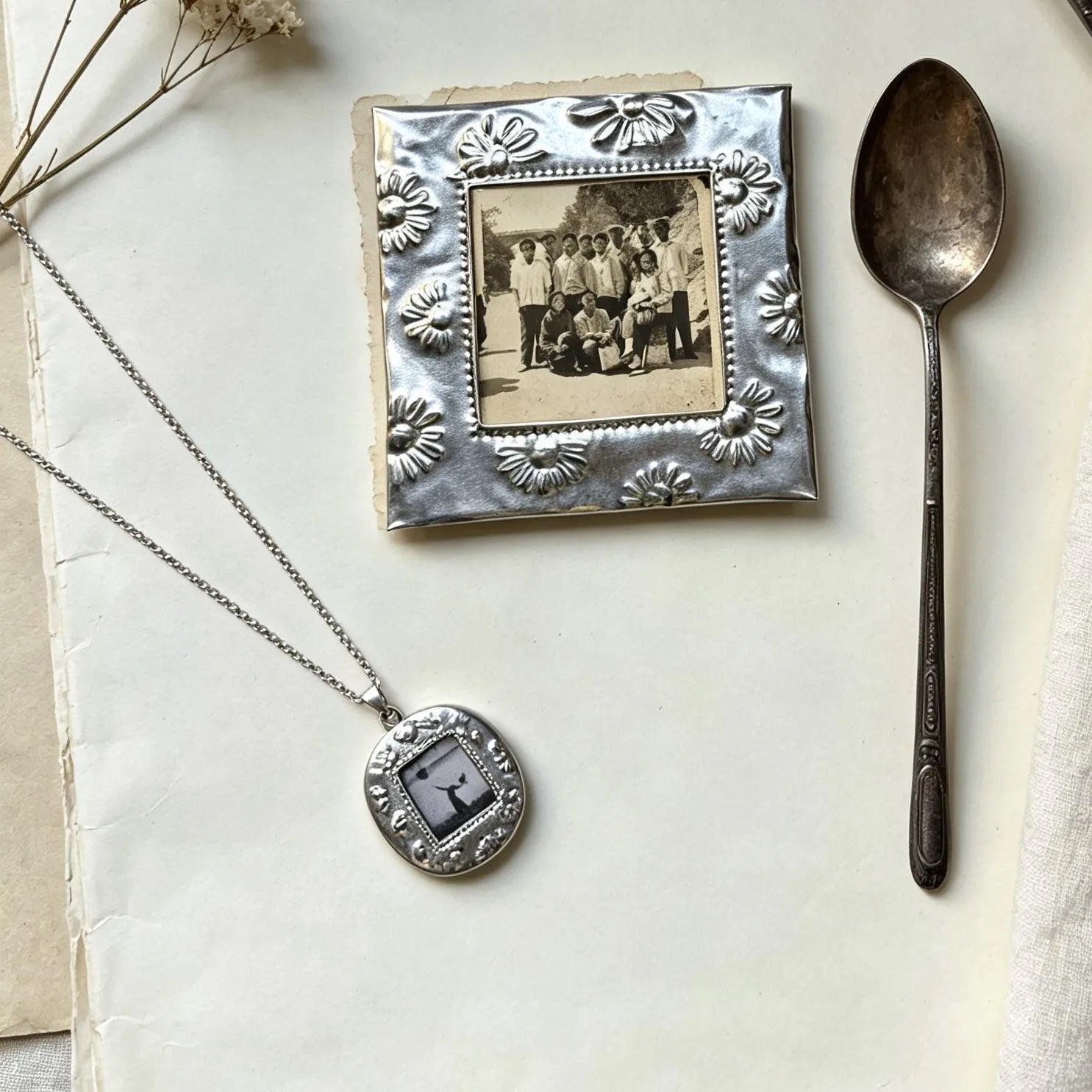 Flat lay of a personalized vintage photo frame necklace on a soft neutral background.