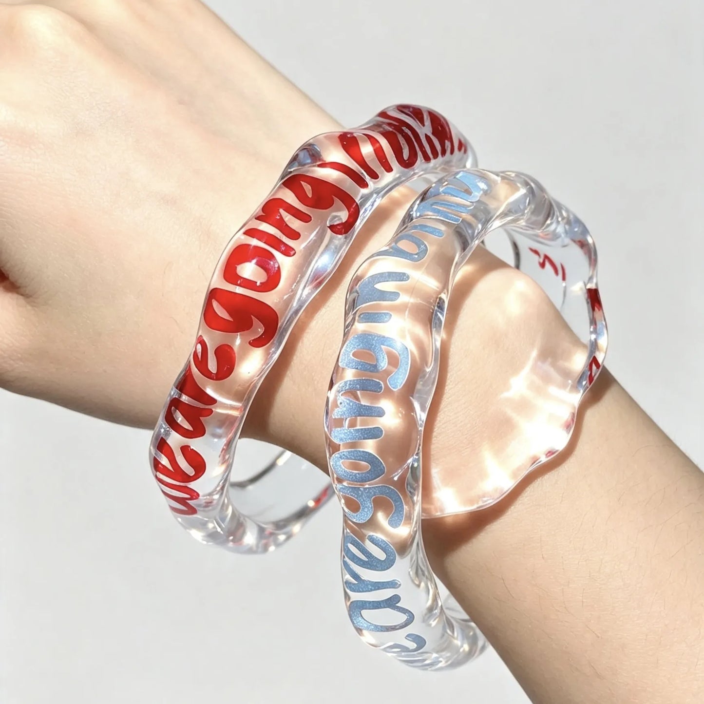 Matching transparent resin bracelets personalized with custom names and quotes.